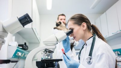 Lab assistant looking through microscope